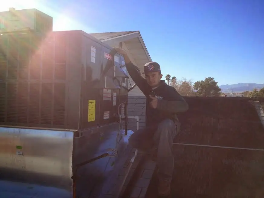 HVAC technician performing Heat Pump Repair on a rooftop unit in Altus